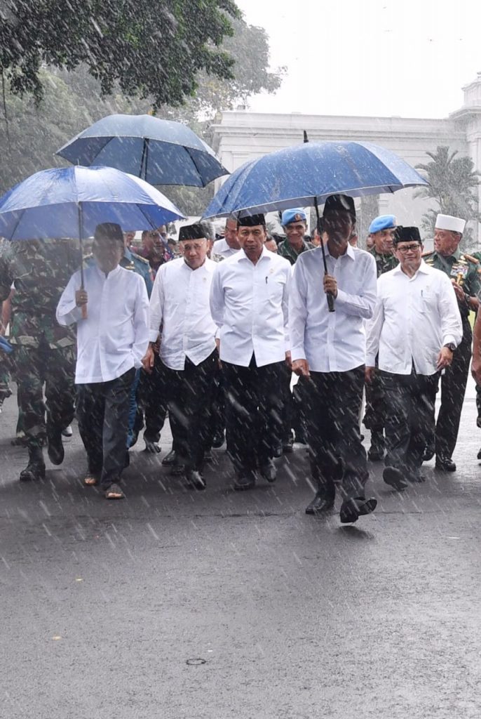 Ditengah hujan Presiden Jokowi bersama Wakil Presiden Jusuf Kalla serta sejumlah menteri berjalan menuju Monas hendak mengikuti doa bersama. FOTO : SETPRES
